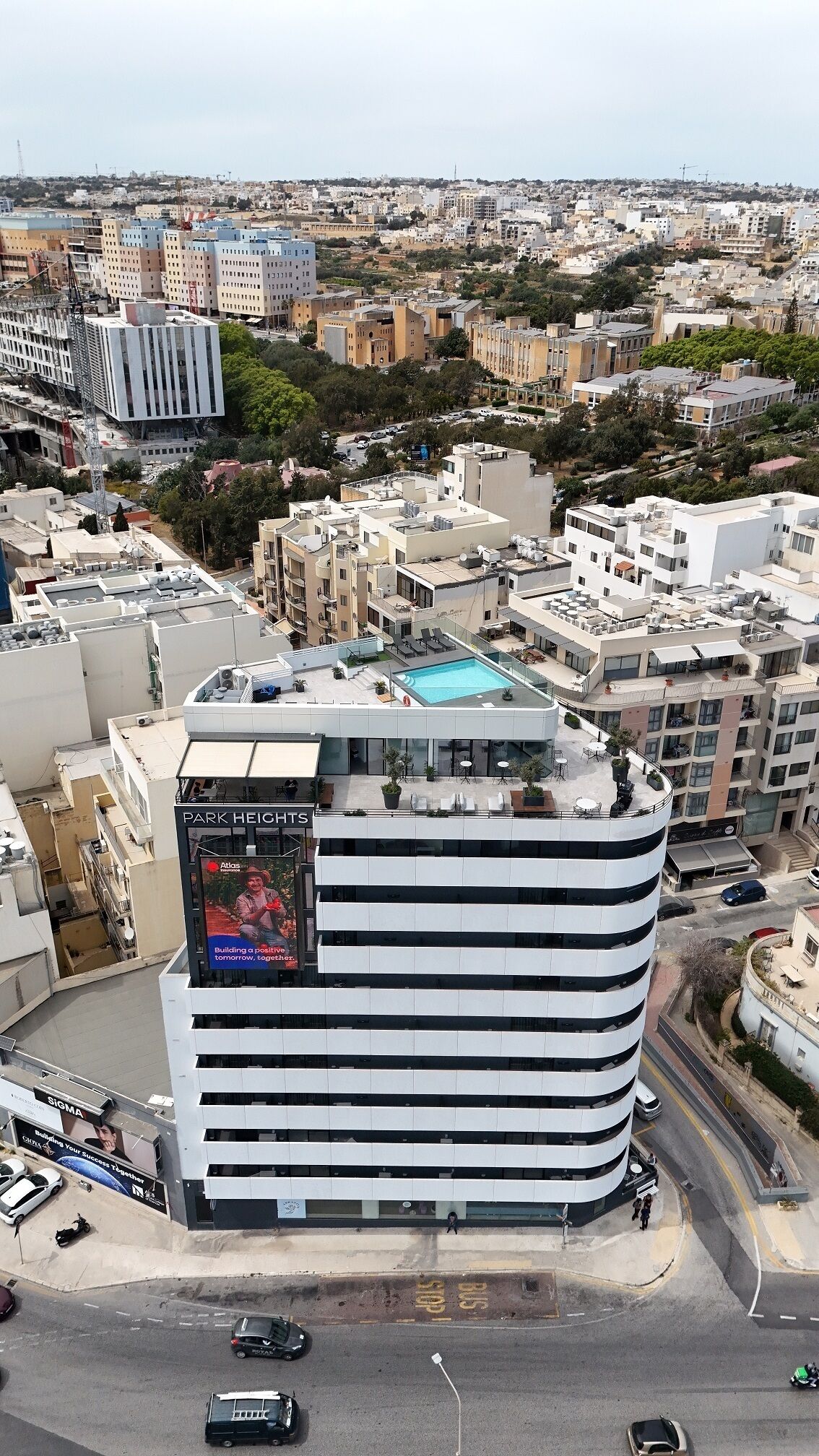 A modern hotel with a rooftop pool, surrounded by urban buildings.