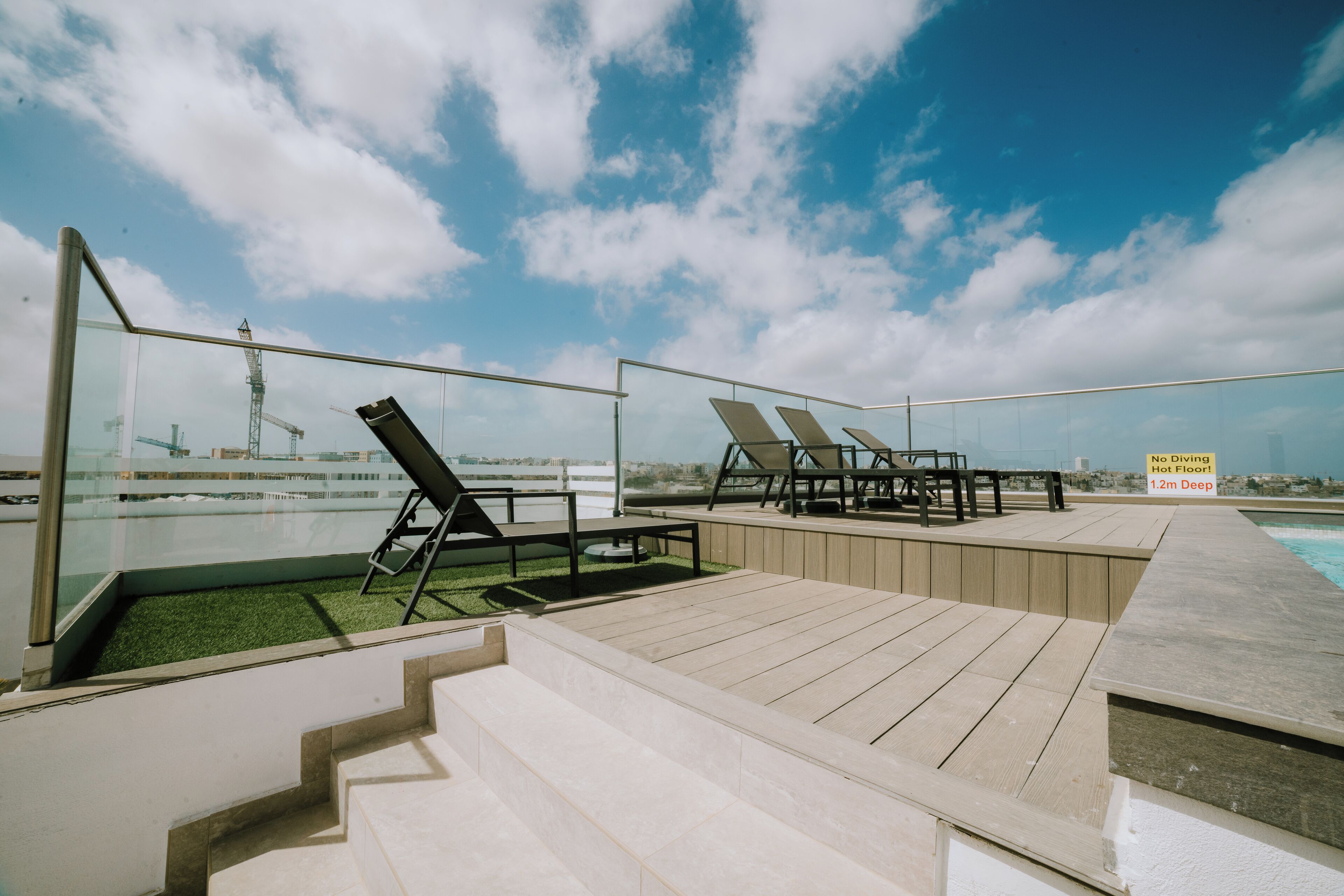 A rooftop deck with outdoor seating, a pool, and a view of the city skyline.