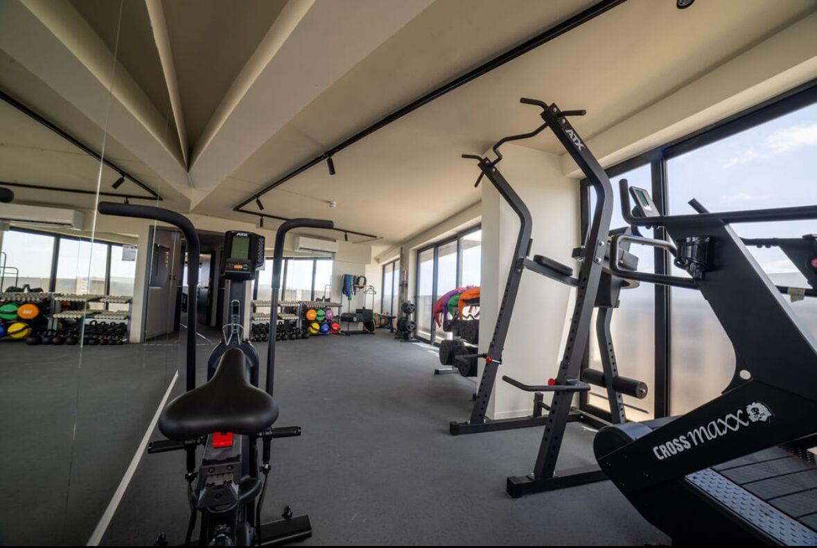 A gym with cardio machines, weightlifting equipment, and dumbbells.