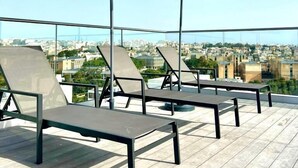 A rooftop terrace with lounge chairs and umbrellas, offering a city view. - Park Heights by the Warren Collection (Msida)