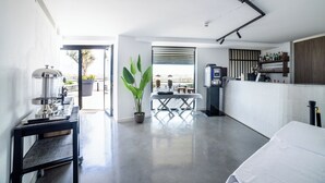 A modern kitchen with a coffee machine, a dining table with chairs, a potted plant, and a bar area with shelves of bottles. - Park Heights by the Warren Collection (Msida)