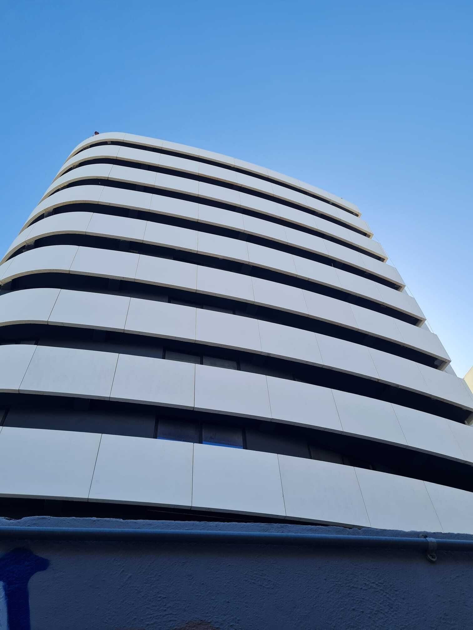 A modern building with a curved facade and horizontal windows.