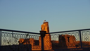 A stone structure with a bird perched on top, surrounded by ornate metal fencing. - Riad Le Petit Joyau (Marrakech)