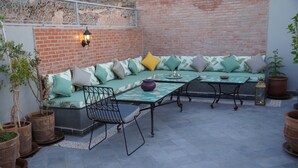 An outdoor seating area with a brick wall, a metal railing, and potted plants. - Riad Le Petit Joyau (Marrakech)