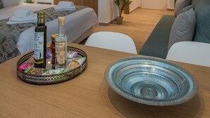 Ein modernes Hotelzimmer mit einem Bett, einer Couch, einem Esstisch mit einer Serviertschale mit Snacks und zwei Pendelleuchten.