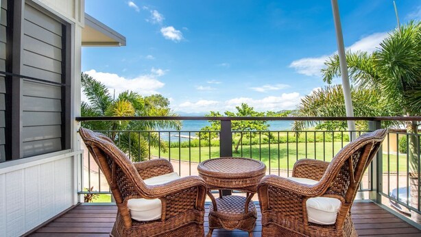 A balcony with wicker furniture and a view of the ocean. - Magnetic Docks Townhouse 5 (Nelly Bay)