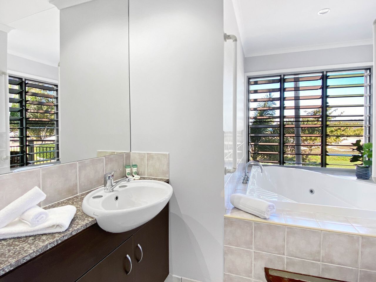 A modern bathroom with a sink, mirror, and bathtub.