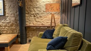 Uma sala de estar aconchegante com um sofá verde, uma mesa de centro de madeira e uma parede de pedra.