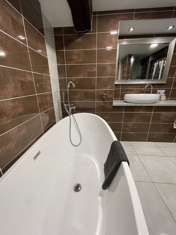 A modern bathroom with a freestanding bathtub, a large mirror, and a vanity with a sink.