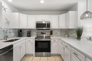 Enjoy cooking in this well-lit kitchen with stainless steel appliances and white cabinetry.
