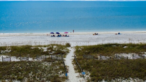 A beach with a clear path leading to the water, umbrellas, and people relaxing. - Sand Buckets Unit B, Ocean View Beach Townhouse (Mexico Beach)