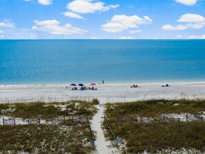 Relax on the beach with comfortable seating and umbrellas, steps from the shore.