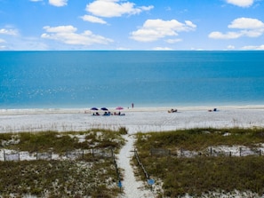 Relax on the beach with comfortable seating and umbrellas, steps from the shore.