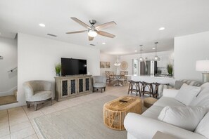 Relax in this stylish living room with a large sofa, wicker ottoman, and flat-screen TV.