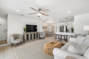 Relax in this stylish living room with a large sofa, wicker ottoman, and flat-screen TV.