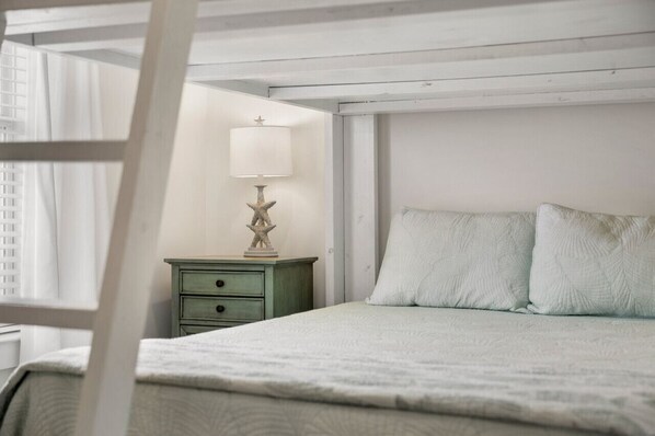A bedroom with a bed, a nightstand, a lamp, and a window with curtains.