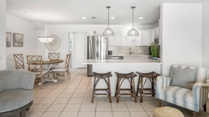 A modern kitchen with a central island, bar stools, and pendant lighting. - Sand Buckets Unit B, Ocean View Beach Townhouse (Mexico Beach)