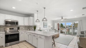 A modern kitchen with white cabinetry, stainless steel appliances, and pendant lighting. - Sand Buckets Unit B, Ocean View Beach Townhouse (Mexico Beach)