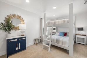 A bunk bed with a ladder, a white dresser with a mirror, and a small stool. - Sand Buckets Unit A, Ocean View Beach Townhouse (Mexico Beach)