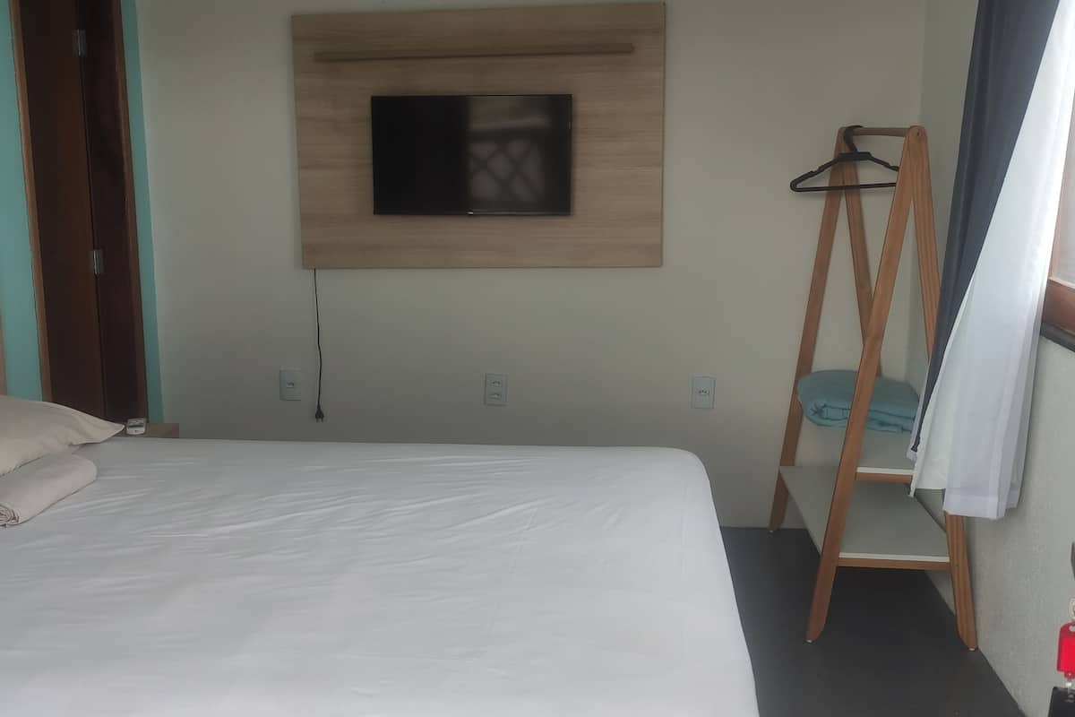 Una habitación de hotel con cama, televisor montado en la pared y escalera de madera.