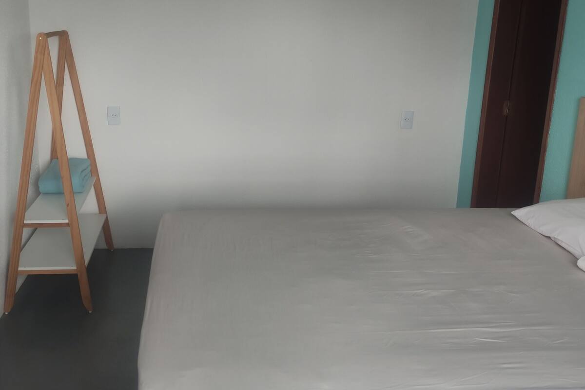Un dormitorio con una cama, una escalera de madera, un televisor montado en la pared y una puerta.