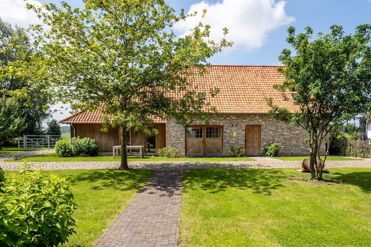 A stone building with a tiled roof, a paved pathway, and green lawns.