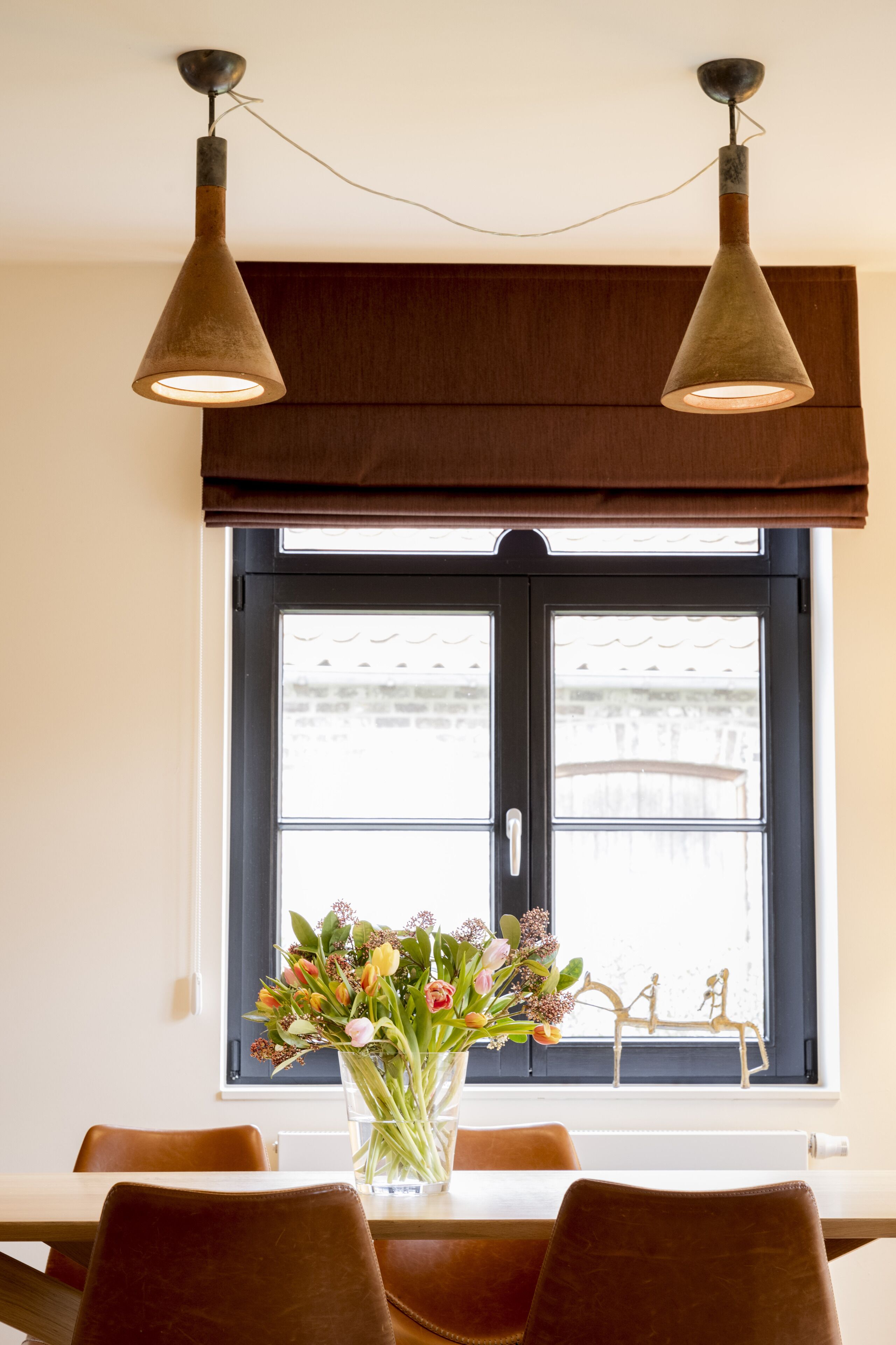 Et spiseområde med et bord, stole og en vase med blomster.