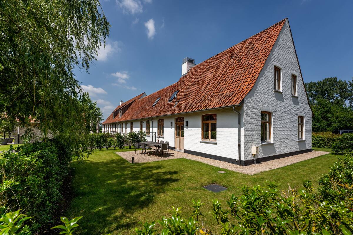 A two-story house with a sloped roof, a well-maintained lawn, and a small patio area.