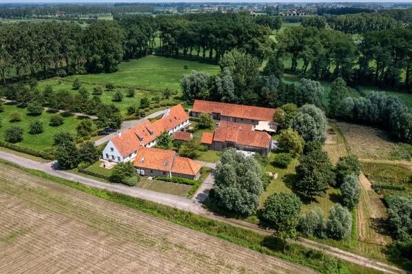 An aerial view of a rural property with multiple buildings, surrounded by fields and trees.