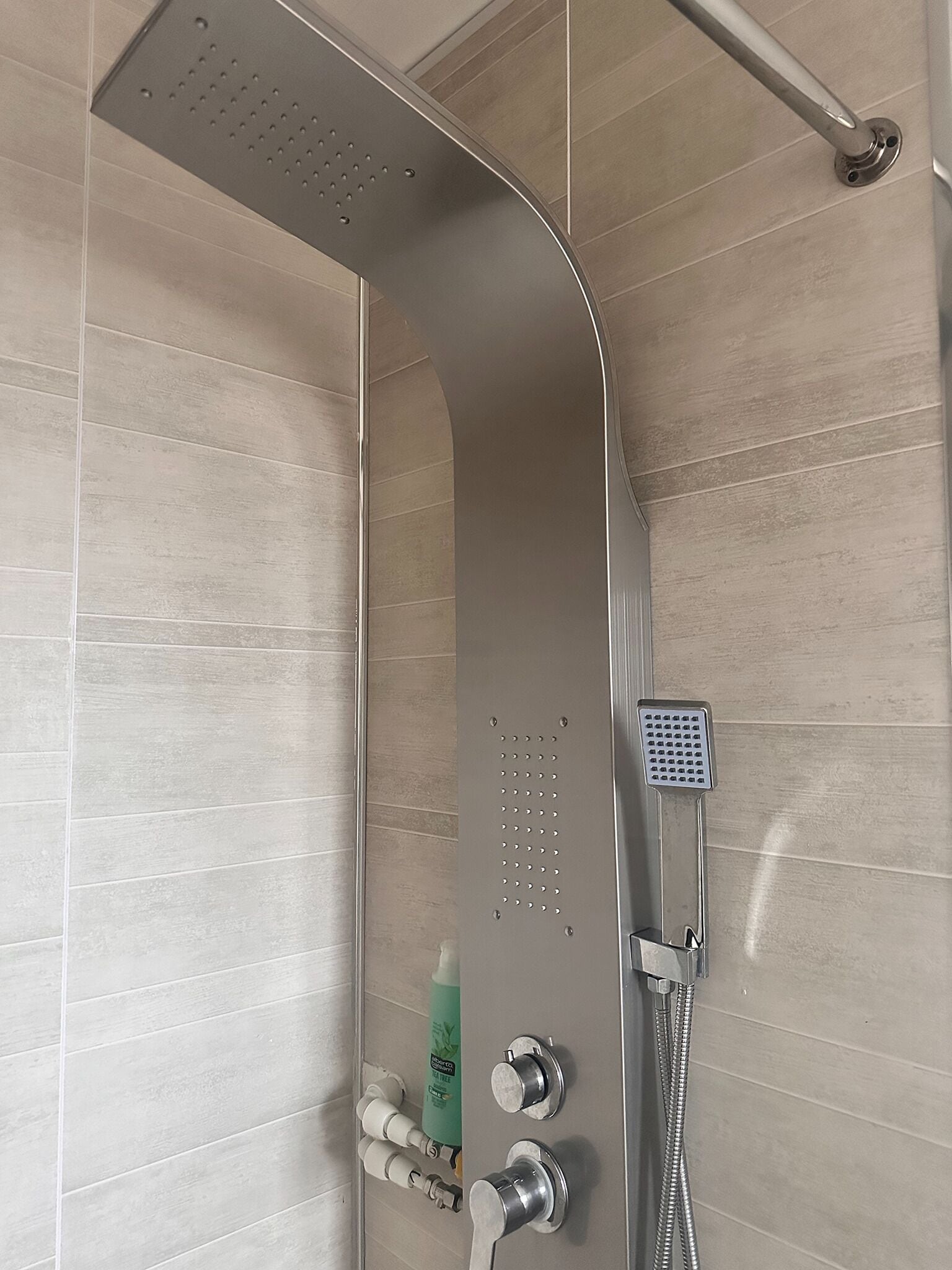 A modern shower with a handheld showerhead, a fixed showerhead, and a rain shower head.