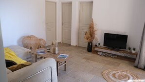 A modern living room with a sofa, coffee table, TV, and decorative items. - Résidence Licciola (Olmeto)