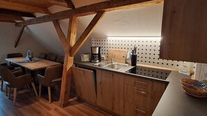 Una cocina con armarios de madera, una mesa de comedor con sillas, una cafetera y un lavabo.
