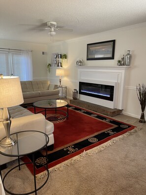 Cozy living space with a comfortable sofa, glass coffee table, and fireplace.