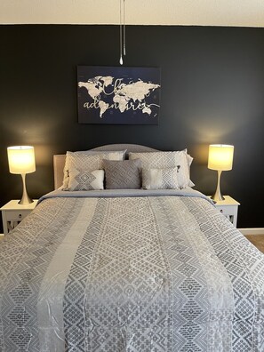 Cozy retreat with a large bed, patterned bedspread, and world map artwork.
