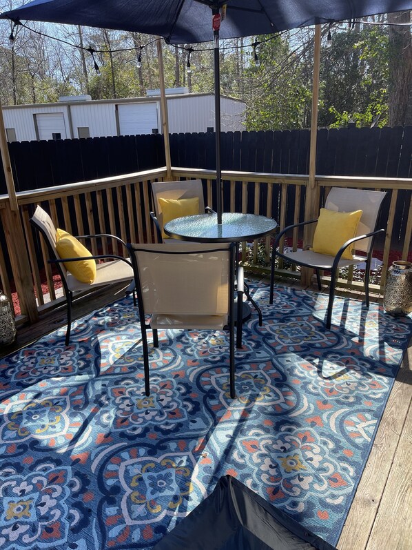 Relax in style with a round table and four comfortable chairs, set amidst a beautifully patterned rug and shaded by a stylish umbrella.