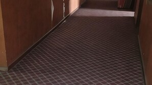 Un couloir doté d’un sol à motifs, de murs en bois et d’une porte au fond.