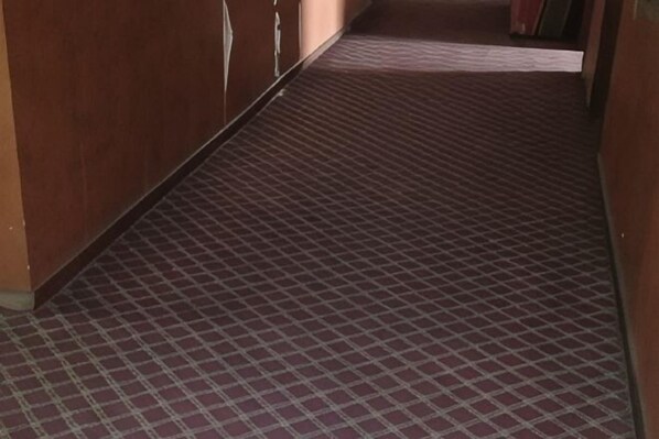 A corridor with patterned flooring, wooden walls, and a door at the end. - Taihui Business Hostel (Chongqing)