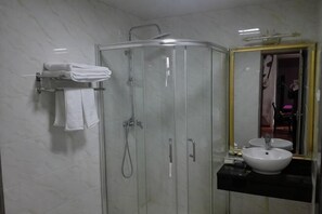 A bathroom with a glass-enclosed shower, a sink with a mirror, and a towel rack. - Taihui Business Hostel (Chongqing)