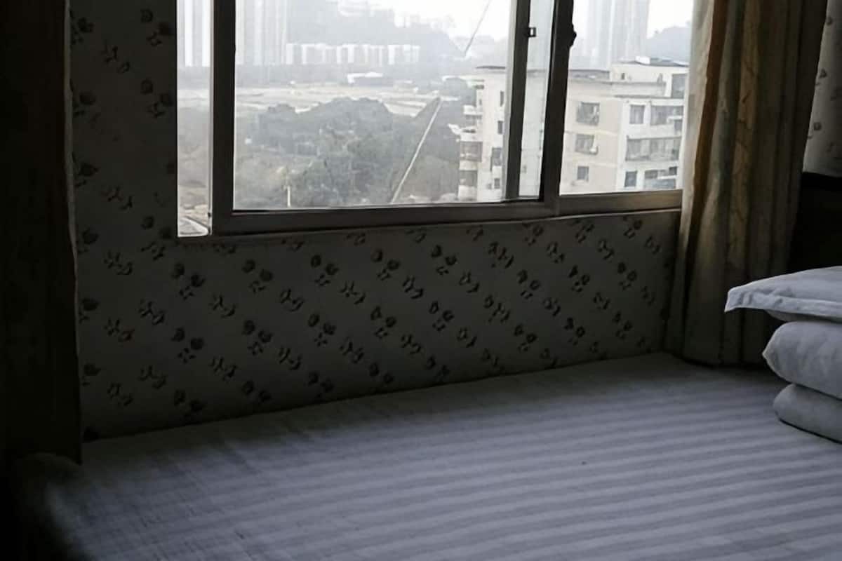 A hotel room with a large window, a bed, and a patterned wall.