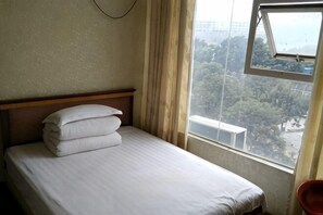 A single bed with white linens, a wooden headboard, and a window with a view of trees and buildings. - Taihui Business Hostel (Chongqing)