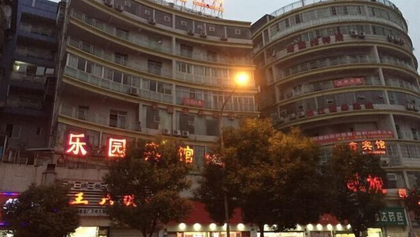 Un hôtel à plusieurs étages, doté d’une façade incurvée, de nombreux balcons et d’une enseigne lumineuse.