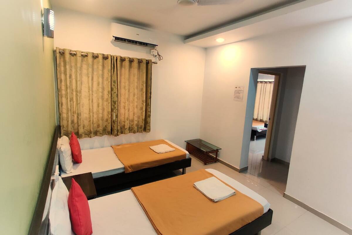 A hotel room with two beds, a small table, and a ceiling fan.