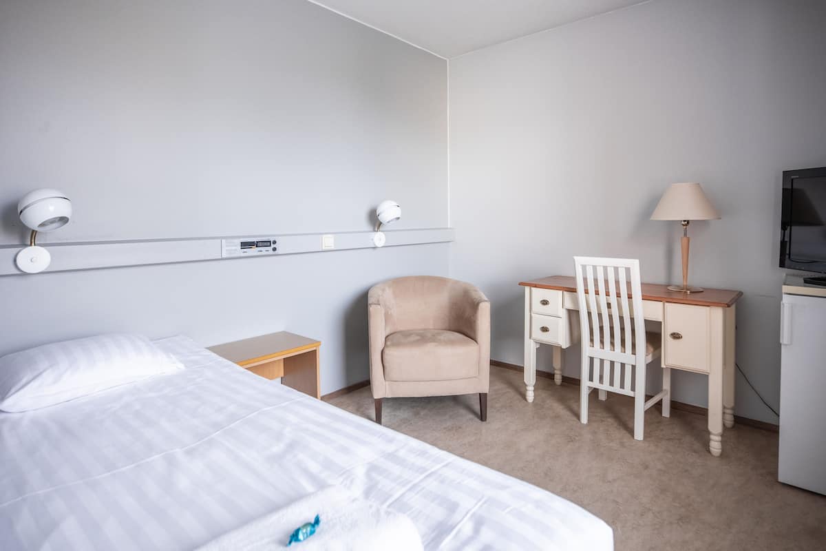 Une chambre d’hôtel équipée d’un lit, d’un bureau, d’une chaise, d’une lampe et d’un téléviseur.