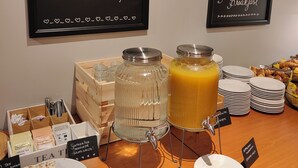 Een ontbijtbuffet met diverse etenswaren en drankjes, inclusief een bord waarop staat 'ALL YOU NEED is love and a Peera Breakfast'.