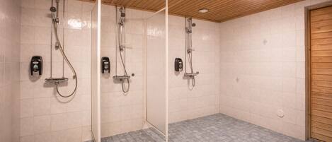 Un área de ducha con tres cabezales, techo de madera y paredes con azulejos.