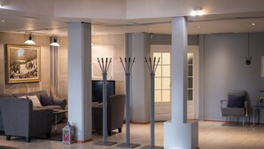 Een moderne woonkamer met een pooltafel, grijze banken, een schilderij en hoge vloerlampen.