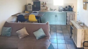A compact living space with a sofa, dining table, chairs, kitchenette, and a window. - 2-bedroom apartment at the foot of the Pyrenees (Pointis-de-Rivière)