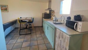 A compact kitchen with a dining area, a microwave, and a sink. - 2-bedroom apartment at the foot of the Pyrenees (Pointis-de-Rivière)