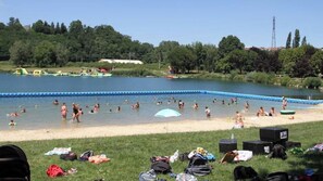 Guests can enjoy swimming and relaxing in the lakeside area surrounded by trees and a distant building.