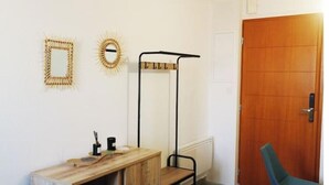 A room with a wooden cabinet, a metal coat rack, a green chair, and a wooden door. - 2-bedroom apartment at the foot of the Pyrenees (Pointis-de-Rivière)